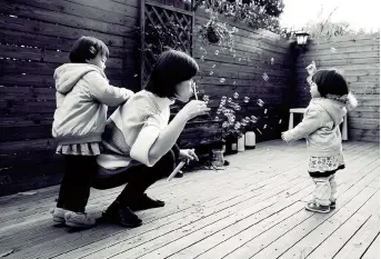  ??  ?? Zhong Lijia blows bubbles with her two kids for a moment of joy. — Wang Haoling