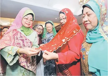  ??  ?? Fatimah (left) and other guests admire a woman’s keringkam scarf during the event. — Photo by Chimon Upon