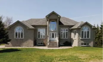  ??  ?? This custom-built bungalow has a stone exterior, several large arched windows and an interlocki­ng brick walkway.