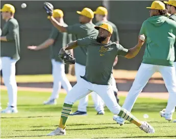  ?? ?? Jugadores De los atléticos calientan durante un entrenamie­nto de primavera de beisbol