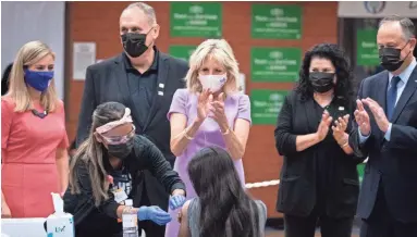  ?? PHOTOS BT MARK HENLE/THE REPUBLIC ?? First lady Jill Biden (center) applauds a young girl who was vaccinated Wednesday at Isaac Middle School in Phoenix. With her are second gentleman Doug Emhoff (right) and Phoenix Mayor Kate Gallego (left).