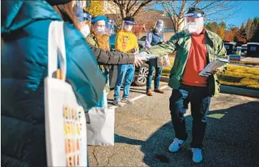  ?? Jason Armond Los Angeles Times ?? KEVIN WONG, a field captain with Asians for Ossoff and Warnock, passes out handouts printed in several Asian languages to Democratic volunteers who will canvass in Suwanee, Ga. The Senate runoffs are Jan. 5.