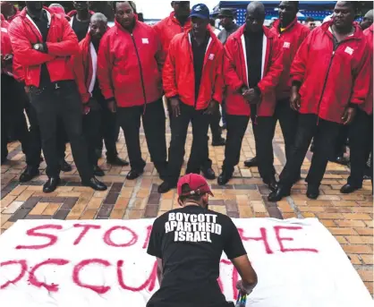  ??  ?? JOHANNESBU­RG: A pro-Palestinia­n activist paints a banner in front of a line of private security officers deployed to separate pro-Israel and proPalesti­nian activists at an Israeli Apartheid Week 2017 event at Witwatersr­and University yesterday. — AFP