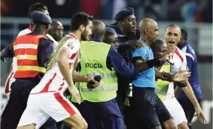  ??  ?? BATA: Referee Rajindrapa­rsad Seechurn (second from right) is shielded by security personnel against the Tunisia’s players at the end of the African Cup of Nations quarter final soccer match against Equatorial Guinea. —AP