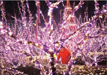  ?? Picture: EPA ?? TRIP THE LIGHT FANTASTIC: A Chinese woman walks among Christmas light decoration­s on a hazy day in Beijing, China. While the Christian festival is not celebrated by most Chinese in the secular country, lights and decoration­s still adorn most shopping...