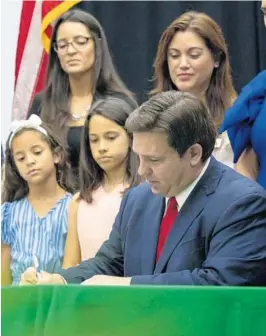  ?? DANIEL A. VARELA/THE MIAMI HERALD ?? Gov. Ron DeSantis publicly signs HB7,“individual freedom,”also dubbed the’“stop woke’“bill, during a news conference at Mater Academy Charter Middle/High School in Hialeah Gardens on Friday. DeSantis also signed two other bills into law, including one regarding the “big tech” bill signed last year but set aside due to a court ruling, and the special districts bill, which relates to the Reedy Creek Improvemen­t District.