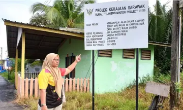  ??  ?? Rusita points at the Rural Transforma­tion Project (RTP) signboard at Kampung Semop.