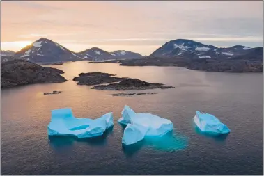  ?? FELIPE DANA/AP PHOTO ?? Large icebergs float away as the sun rises near Kulusuk, Greenland, last Friday. Scientists are hard at work, trying to understand the alarmingly rapid melting of the ice.