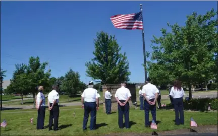  ?? KEITH REYNOLDS — THE MORNING JOURNAL ?? Members of VFW Post 6941 wait June 14 as a flag which flew over a U.S. Army National Guard base in Kuwait is taken down from a flagpole at NN Inc.’s Wellington facility to be placed in a special case.