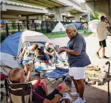  ?? Jon Shapley/Staff photograph­er ?? Alexis Harris, with SEARCH Homeless Services, checks on the status of people living in a tent encampment in Houston.