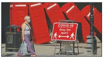  ?? (File Photo/AP/ Matt Dunham) ?? A sign requesting people stay 2 meters apart to try to reduce the spread of covid-19 is displayed in June in front of “Out of Order,” a 1989 red phone box sculpture by British artist David Mach in Kingston upon Thames in southwest London.