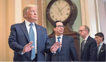  ?? EVAN VUCCI/AP ?? President Donald Trump, standing alongside Treasury Secretary Steven Mnuchin, has begun to strike a less optimistic tone when talking about the coronaviru­s and what the threat could do to the U.S. economy.