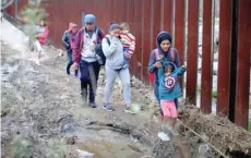 ?? — Reuters ?? Migrants from Honduras, part of a caravan of thousands from Central America trying to reach the United States, walk next to the border fence as they prepare to cross it illegally, in Tijuana, Mexico, on Friday.