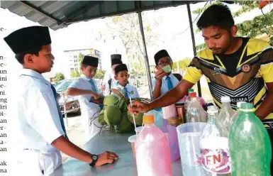  ?? FOTO: ?? HAMZAH (kanan) mencari rezeki dengan bekerja sebagai penjual air minuman di kedai milik rakannya.