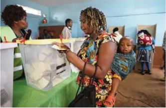  ??  ?? NAIROBI: A Kenyan woman carries her baby on her back as she casts her vote in Gatundu, north of Nairobi yesterday. — AP