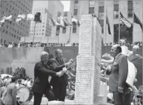  ?? RAY HOWARD — THE ASSOCIATED PRESS FILE ?? In this file photo, David Rockefelle­r, second left, Rockefelle­r Center chairman and Center President Richard H. Voell, left, and New York City Board of Education President Joseph Barker, right, begin to slice up an eight-foot-tall culinary replica of...