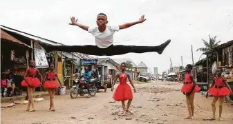  ?? Sunday Alamba / Associated Press ?? Ballet student Anthony Mmesoma Madu, center, dances in the street as fellow dancers look on in Lagos, Nigeria. Video showing the 11-year-old dancing barefoot in the rain went viral on social media.