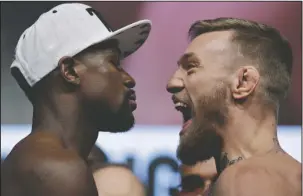  ?? The Associated Press ?? LOOK US OVER: Floyd Mayweather Jr., left, and Conor McGregor stare each other down the weighin Friday for their fight tonight in Las Vegas.