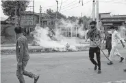  ?? Dar Yasin / Associated Press ?? Kashmiris take cover from tear gas shells during a protest after Friday prayers in Srinagar in the Indian-controlled region of Kashmir.