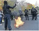  ??  ?? COUNTER-DEMO Protestor sets fire to blue Stars and Stripes in front of police