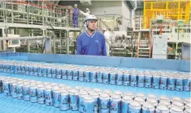  ?? PHOTO BY KOJI SASAHARA/AP ?? Asahi Breweries plant manager Shinichi Uno watches the production line in Moriya near Tokyo. The human’s job is to make sure the machines do the work right and to check on the quality the sensors are monitoring. Uno says, “Although machines make...