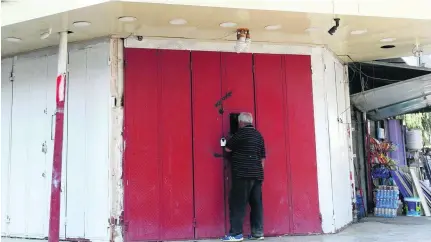  ?? Sabah Arar / AFP ?? An Iraqi buys liquor illegally from a closed shop in Baghdad. Iraq’s ban on alcohol sales has drawn widespread condemnati­on.