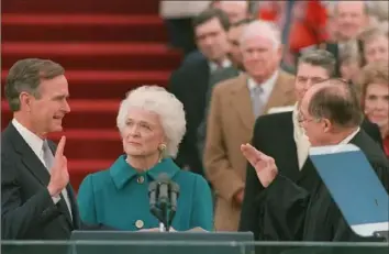  ?? Bob Daugherty/Associated Press ?? President George H.W. Bush raises his right hand as he is sworn into office as the 41st president of the United States by Chief Justice William Rehnquist outside the west front of the Capitol on Jan. 20, 1989, as first lady Barbara Bush holds the Bible for her husband.