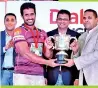  ??  ?? Havelock SC Skipper Niroshan Fernando receiving the Clifford Cup from Harin Fernando, Minister of Sports and Supun Weerasingh­e, Group Chief Executive, Dialog Axiata PLC