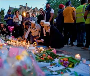  ?? AFP ?? People light candles in front of floral tributes in albert square in manchester, northwest england in solidarity with those killed and injured in the terror attack at the ariana Grande concert . —