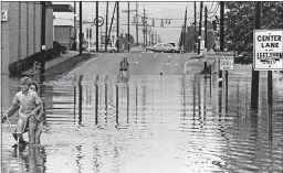  ??  ?? Kids ride a bicycle through the flood at Whipple Road near Route 30 in Canton on July 5, the day after the storm.