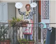  ?? ANDREAS SOLARO / AFP VIA GETTY IMAGES ?? A woman uses pot lids for cymbals as she takes part in the music flash mob “Look out from the window, Roma mia!”