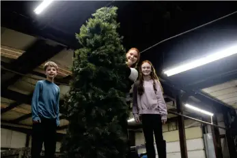  ?? (Matt Hutcheson/News-Times) ?? Rayson, along with Valerie and Kamdyn Smith, set up the Christmas tree on Union County’s Grand Marshal parade float Tuesday evening. A group gathered with the El Dorado-Union County Chamber of Commerce’s Karen Hicks at the Union County Highway Department shop on Tuesday to prepare the float for the annual El Dorado Christmas parade, which begins tonight at 7 p.m.