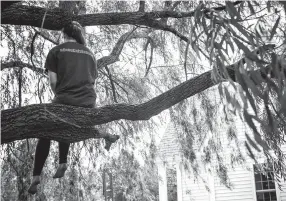  ?? ANDREA MORALES/NEW YORK TIMES ?? Hailey Case, one of the Marshall County High students calling for gun restrictio­ns since the shooting that killed two at the school, shows her #enoughisen­ough T-shirt, sitting in a tree at a friend’s home in Calvert City, Ky., on May 12.