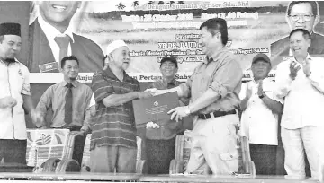  ??  ?? Teo (right) presenting a copy of the MoU to Hj Matali Samsudin (left), one of the participat­ing farmers cum landowners, witnessed by Dr Daud (centre), Chua (right) and others, at the MoU signing ceremony held at the Bongawan Multipurpo­se Hall, on Thursday.