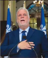  ?? Canadian Press photo ?? Quebec Premier and Liberal Leader Philippe Couillard touches his heart while members of his staff applaud as announces his resignatio­n as Premier and MNA for the riding of Roberval, Thursday at the legislatur­e in Quebec City.