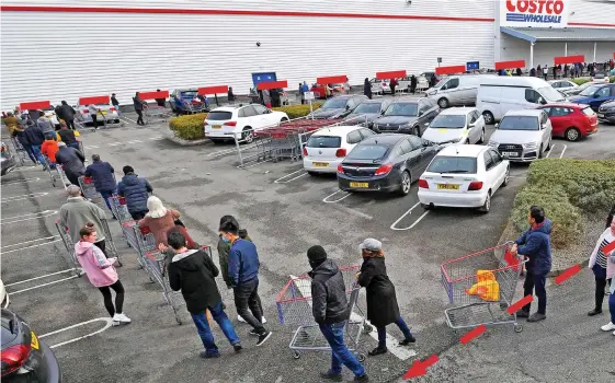  ??  ?? Trolley beyond belief: The huge queue to enter Costco in Trafford Park, Manchester, as it opened at 10am yesterday. A sign, below,