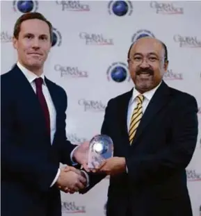  ??  ?? Mohamed Rafique menerima anugerah Bank Islam terbaik dunia daripada Pengarah Urusan Global Finance untuk Eropah dan Asia, Richard Scholtz.