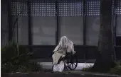  ?? DAMIAN DOVARGANES — THE ASSOCIATED PRESS ?? A homeless person sits on a wheelchair under rainy weather on Sunset Blvd. in the Echo Park neighborho­od of Los Angeles Monday.