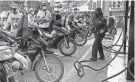  ?? HAU DINH/AP ?? People wait for the gas pump in Hanoi, Vietnam, Sunday. A motorcycle taxi driver in Vietnam turns off his ride-hailing app rather than burn precious fuel during rush-hour backups.