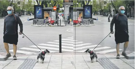  ?? Picture: AFP ?? A man wearing a mask walks his dog past a shop window in Madrid at the weekend, during the hours allowed by government to exercise, for the first time since the beginning of a national lockdown. Spaniards are again allowed to leave their homes to walk, or play sports, after 48 days of strict confinemen­t.