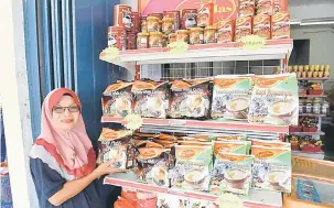  ?? — Gambar Bernama ?? PENDAPATAN 6 ANGKA: Hamidah menunjukka­n produk jualan yang terdapat di kedainya yang terletak di Parit Putat, Sungai Rambai. Beliau meraih pendapatan sehingga RM120,000 sebulan setelah menyertai projek ABR1M yang diperkenal­kan oleh FAMA.