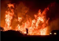  ?? AP Photo/noah Berger, ?? In this Dec. 6, 2017, file photo, a motorist on Highway 101 watches flames from the Thomas fire leap above the roadway north of Ventura.