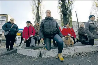  ?? Carolyn Cole Los Angeles Times ?? RESIDENTS of Borodyanka, Ukraine, kneel as the funeral procession for soldier Oleksii Kozlenko passes on Tsentralna street. Most of the town’s mobilized men are on the front lines in the east.