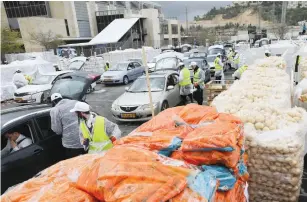  ?? (Marc Israel Sellem/The Jerusalem Post) ?? WORKERS DISTRIBUTE food at the annual Kimcha D’pischa yesterday.