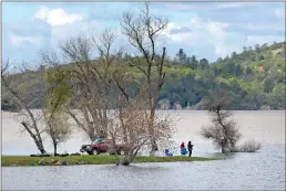  ??  ?? LEFT: Two fishermen from Marysville sit on the banks of Collins Lake on March 14 in Browns Valley. RIGHT: Justin Havens and his daughter Caycie, 7, of Colusa float on an inflatable raft in 2013 at Collins Lake in Yuba County.