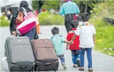  ?? GEOFF ROBINS/GETTY IMAGES ?? Asylum seekers walk along Roxham Road near Champlain, N.Y., on Aug.6, making their way towards the Canada/U.S. border.