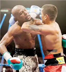  ??  ?? En los asaltos finales el combate se tornó rudo. Aquí Maidana usa su antebrazo para ejercer presión en el cuello de Floyd.