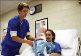  ?? AP PHOTO/CARRIE ANTLFINGER ?? Nathan Miller, 19, stands over fellow student Camille Sem, 17, in a certified nursing assistant class at New Berlin Eisenhower Middle/High School in New Berlin, Wis. Miller is forgoing a summer job to play baseball and take the class, to help make him...