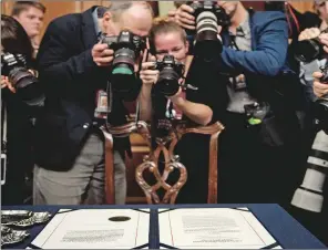  ?? (AFP) ?? Reporters gather around the Articles of Impeachmen­t against US President Donald Trump.