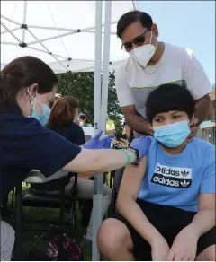  ?? Julia malaKie / loWell sun ?? the city of lowell sponsored a block party at stem academy to support coVid-19 vaccinatio­n efforts. cataldo ambulance vaccinator brooke skehan gives shaurya sanariya, 12, of lowell, his first coVid-19 vaccine, and shaurya’s father rajesh sanariya looks on. people had a choice of pfizer, moderna, or J&J.